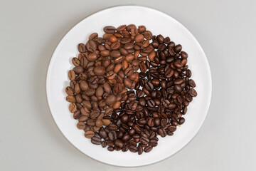 Medium and dark roasted coffee beans separately on one plate