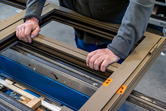 Technicien qui intervient sur une fen&ecirc;tre en aluminium. Gros plan sur les mains pos&eacute;es sur la fen&ecirc;tre.