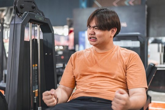 Overweight man struggles to stay motivated during exhausting gym workout