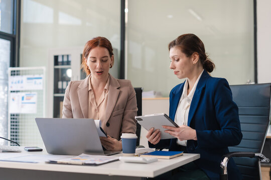Two business woman executive leaders team using laptop working on computer at work desk.
