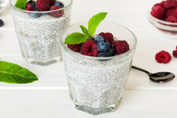Healthy breakfast or morning with chia seeds vanilla pudding raspberry and blueberry berries on table background, vegetarian food, diet and health concept. Chia pudding with raspberry and blueberry