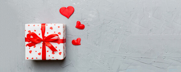 Valentine day composition: red gift box with bow and heart. Christmas present. View from above. Space for text. Holday greeting card