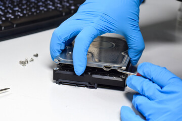 Computer technician wearing gloves with a screwdriver Dismantling and repairing hard disks on a work desk