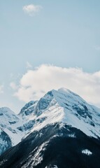 Snow-Capped Mountain Peak against a Light Blue Sky with Cloud Formations on a Winter Day, Natural Beauty