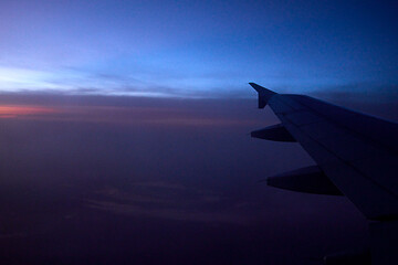 Fototapeta premium Flug bei Sonnenuntergang – Magische Farben über der Erde. Faszinierende Luftaufnahme aus einem Flugzeug während des Sonnenuntergangs. Die Bilder zeigen einen atemberaubenden Blick aus dem Fenster.