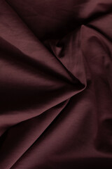 Obraz premium Close-up of burgundy fabric, showing soft textures and folds. Ideal for backgrounds or showcasing textiles with a rich, warm color.