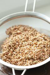 Buckwheat in a strainer, showcasing its natural textures and colors. A simple, healthy grain ready for preparation and cooking.