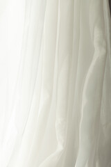 Obraz premium Soft white fabric drapes gracefully, creating a serene and airy ambiance with its gentle folds and light-filtering texture. Simple elegance.