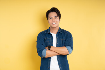 Portrait of handsome Asian man posing on yellow background