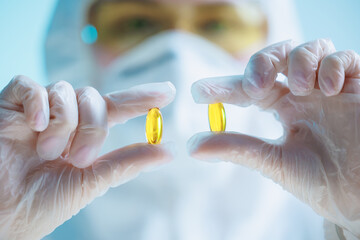 Quality control in medical production: worker examining omega 3 capsules in sterile environment