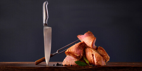 Kasseler mit Messer und Spiess auf Holzplatte, Fleisch, Stahlmesser, Fleischgabel, 