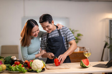 A man and a woman are cutting a red pepper