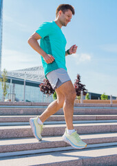 Man jogging down outdoor stairs in athletic wear during bright sunny day at modern urban park