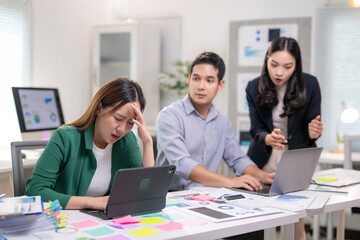 A woman is sitting at a desk with a laptop and a tablet