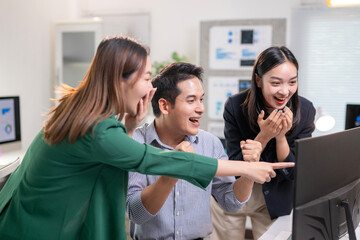 Three people are in a room, one of them pointing at a computer screen