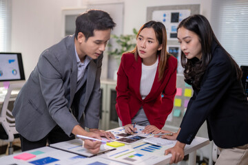 Three people are sitting at a table with a white board