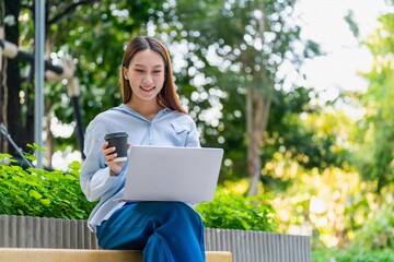 Young Asian Woman Using Laptop While Taking a Coffee Break Outdoors a Modern Urban Greenery Office Settings
