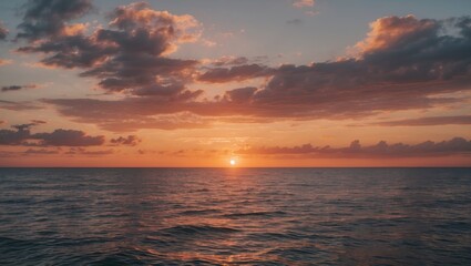 Obraz premium Sunset over calm ocean water with clouds and vibrant sky colors reflecting on the surface during twilight time