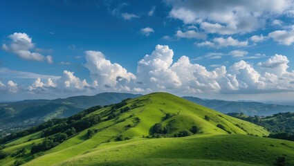 Obraz premium Rolling green hills under a blue sky with fluffy white clouds in a mountainous landscape on a sunny day