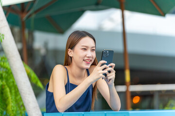 Fototapeta premium Young Asian Woman Using Phone Outdoors