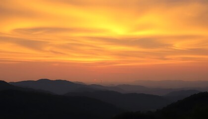 Fototapeta premium Stunning sunset over a vast mountain range, vibrant orange and yellow sky, silhouettes of distant hills, hazy atmosphere, calm peaceful scene, beautiful nature photography