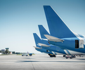Side shot of thee airplanes with blue tails at the airport. Three airplanes in a row parked on...
