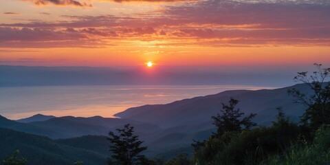 Fototapeta premium Sunset over mountains and lake with vibrant colors reflecting on water and silhouette of trees in foreground during twilight hours