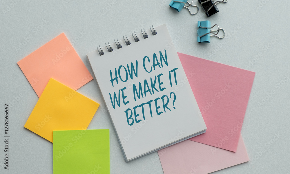 Poster a notebook with a blue pen and a pink pen with the words how can it make it better written on it