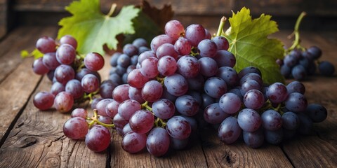 Obraz premium Fresh red grapes with green leaves on rustic wooden surface close-up photography