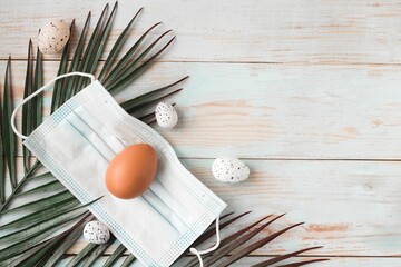 Chicken egg in face medical mask and palm branch. Easter holiday during the coronavirus pandemic....
