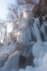 Komplett vereister Wasserfall bei Bad Urach mit den ersten Sonnenstrahlen des Tages.