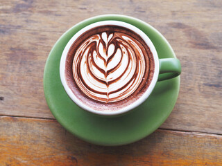 green cup of coffee on wooden table.