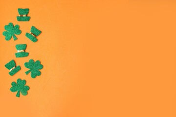 St. Patrick's Day low border paper shamrocks and leprechaun hats on orange background. Copy space...