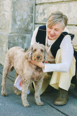 Outdoor portrait of happy mature woman petting labradoodle dog