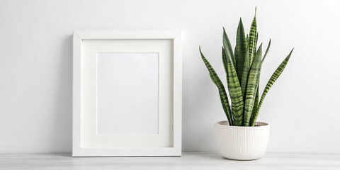 Fototapeta premium Elegant White Frame Mockup Featuring a Sansevieria Plant in a Pot for Stylish Interior Design