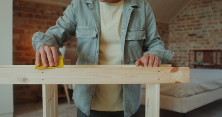 A man and a woman polish a rack with sandpaper in a stylish home interior, they smile and talk