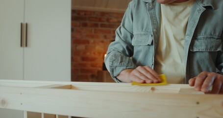 A man polish a rack with sandpaper in a stylish home interior