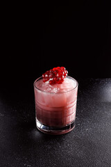 Red cocktail with ice in an old fashioned glass. A piece of pomegranate decorates the refreshing drink. Long alcoholic drink for a bar cocktail card. Party concept for girls.