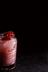 Red cocktail with ice in an old fashioned glass. A piece of pomegranate decorates the refreshing...