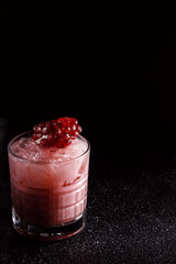 Red cocktail with ice in an old fashioned glass. A piece of pomegranate decorates the refreshing...