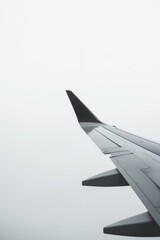 Airplane wing cutting through soft, misty sky evokes sense of tr