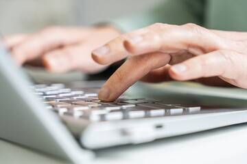Hands typing on a laptop keyboard, close-up of finger pressing key