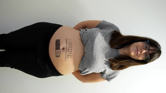 Pregnant woman displaying creative pregnancy progress bar announcement on her belly