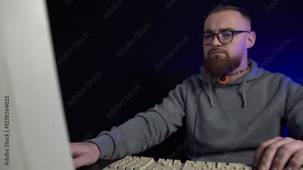 Poster man with glasses working on desktop computer from 1990's in dark room