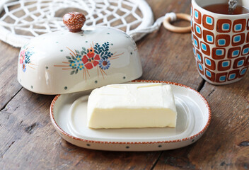 Beautiful ceramic butter dish  with butter briquettes on the kitchen table. Selective focus.