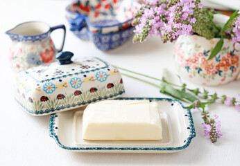 Beautiful ceramic butter dish  with butter briquettes on the kitchen table. Selective focus.