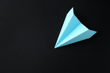 One handmade light blue paper plane on black background, top view. Space for text