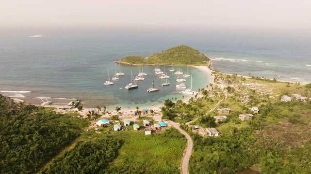 Aerial view of Mayreau in St. Vincent and the Grenadines with lush forest and palm trees up against the tropical water of the bay