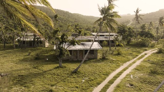 An abandoned resort aerial drone shot in Mayreau in St. Vincent and the Grenadines aftermath of category 4 hurricane Beryl. Sunny day with many palm trees and a dirt road