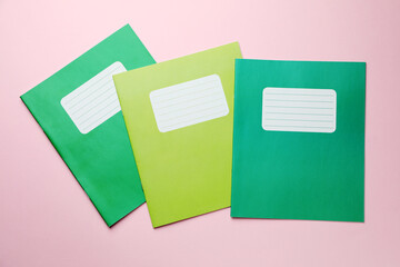 Colorful copybooks on pink background, flat lay. School stationery